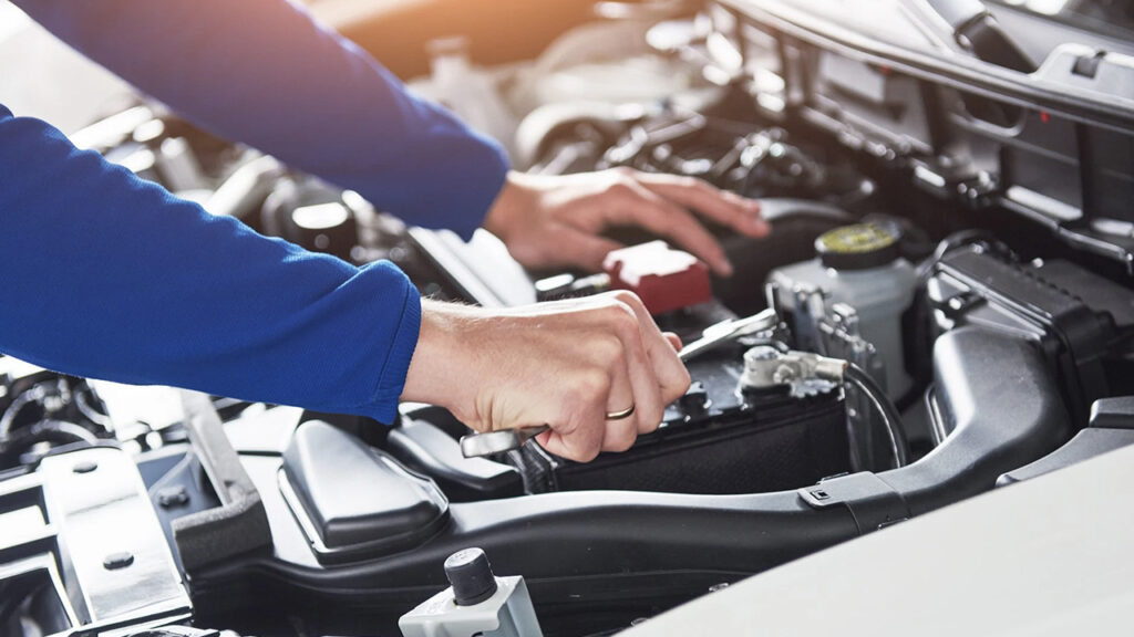 Immagini delle mani di un meccanico che lavorano nel cofano di un auto
